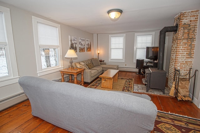 living room with hardwood / wood-style floors, a wood stove, and a baseboard radiator