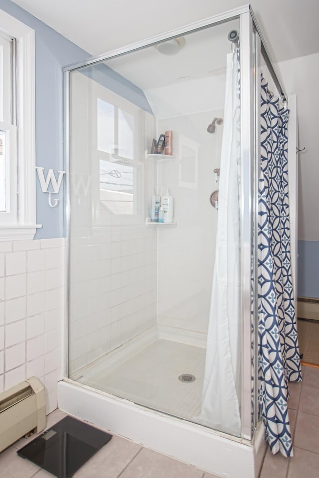 bathroom featuring tile patterned floors, a tile shower, tile walls, and baseboard heating