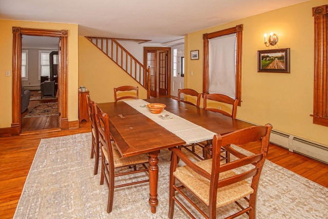 dining area featuring hardwood / wood-style floors, a healthy amount of sunlight, and a baseboard heating unit