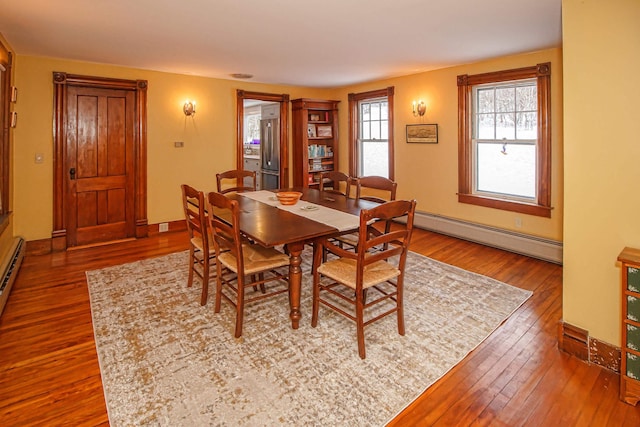 dining area with dark wood-type flooring and a baseboard heating unit