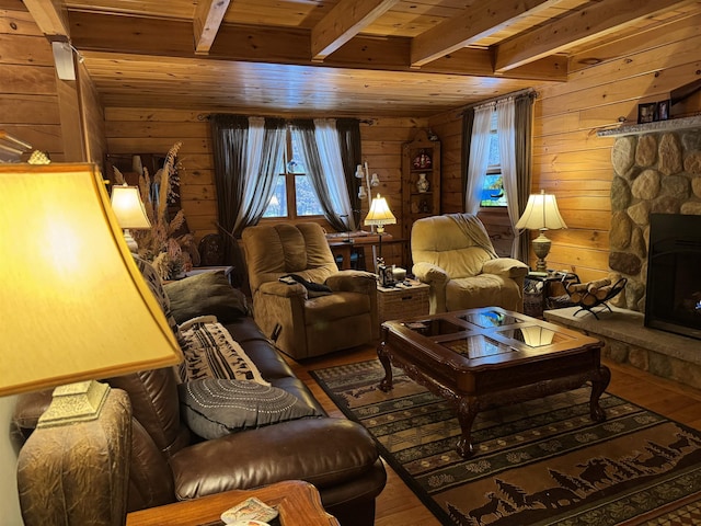 living room with beam ceiling, a stone fireplace, wood ceiling, and hardwood / wood-style flooring