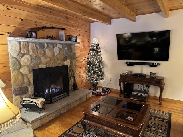 living room with hardwood / wood-style floors, beam ceiling, a stone fireplace, and wood ceiling