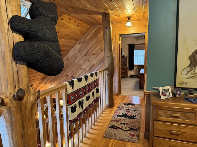 hall with lofted ceiling, wood walls, light wood-type flooring, and wood ceiling