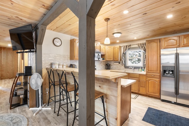 kitchen with a kitchen bar, decorative backsplash, light wood-type flooring, and appliances with stainless steel finishes