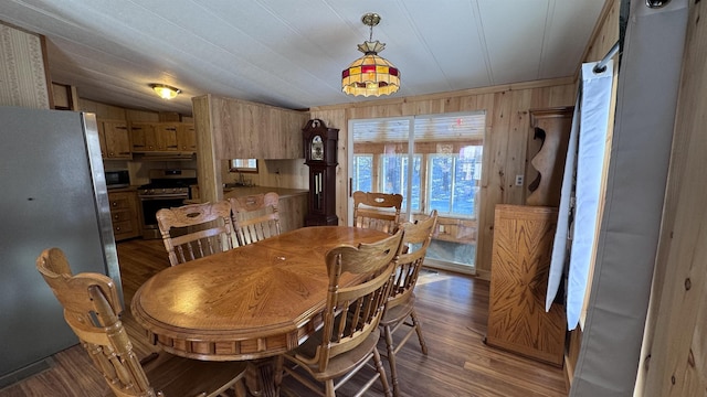 dining space with dark wood-type flooring, vaulted ceiling, and wooden walls