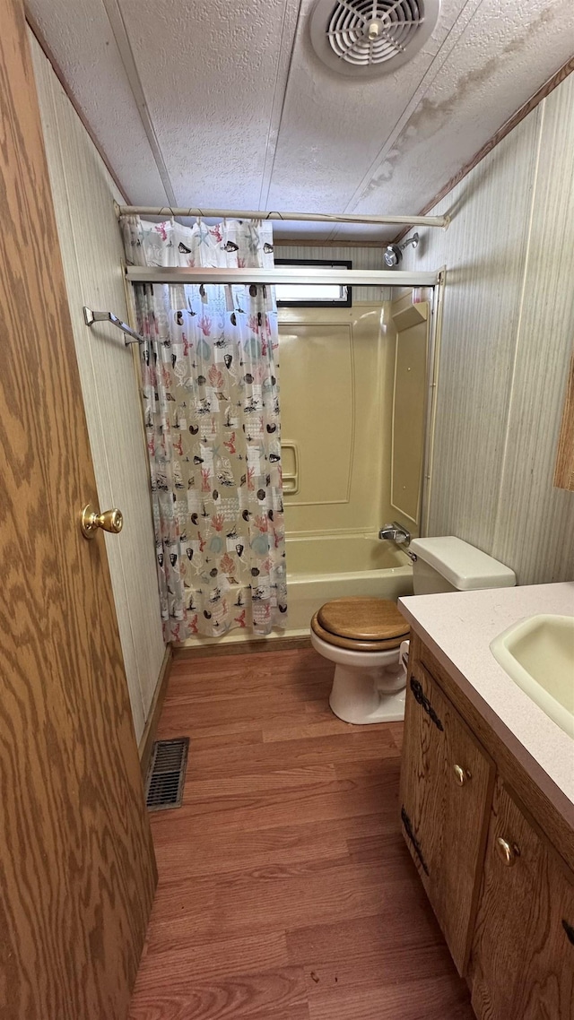 full bathroom featuring vanity, toilet, a textured ceiling, shower / tub combo with curtain, and wood-type flooring