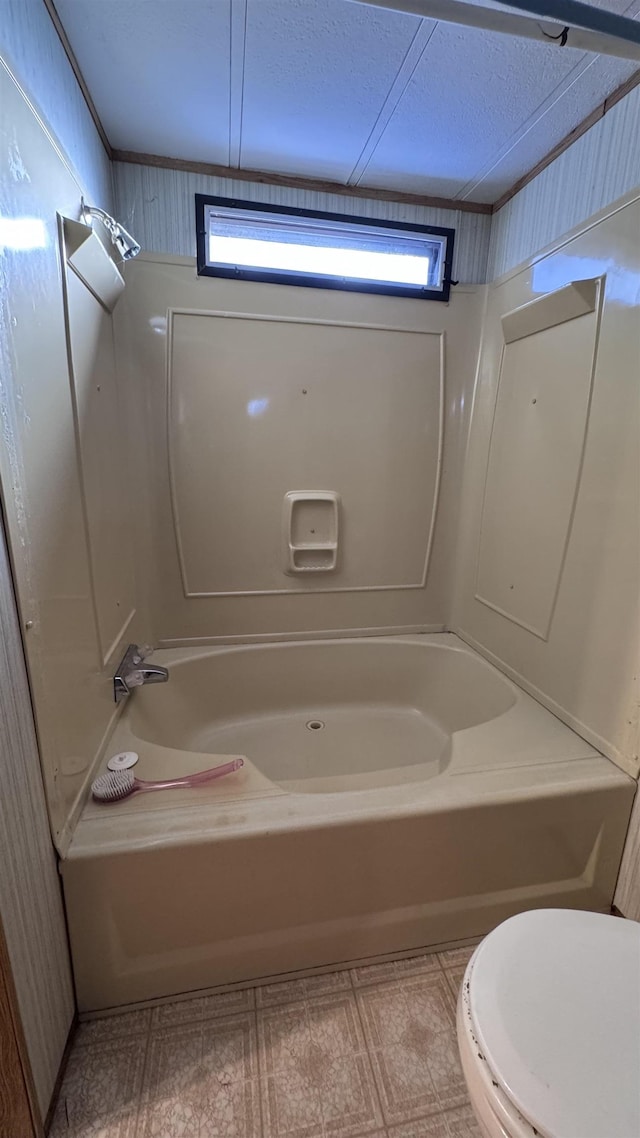 bathroom with a textured ceiling, a healthy amount of sunlight, bathtub / shower combination, and toilet