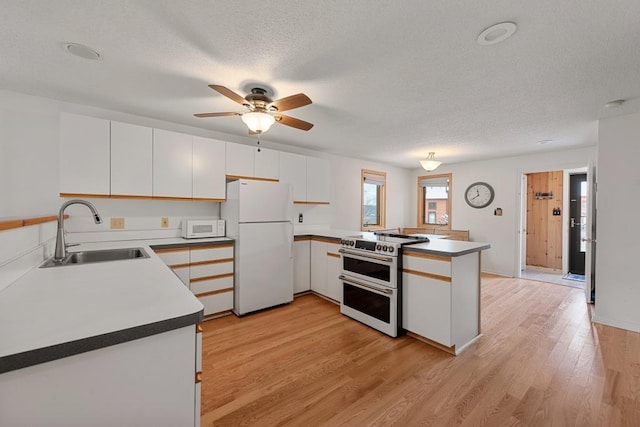 kitchen with white appliances, sink, light wood-type flooring, white cabinetry, and kitchen peninsula