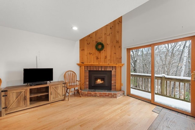 living room with a fireplace, hardwood / wood-style floors, lofted ceiling, and wood walls