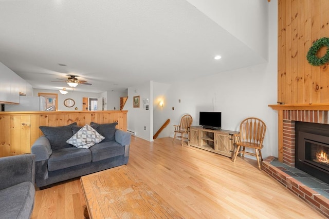 living room featuring ceiling fan, light hardwood / wood-style floors, and a fireplace