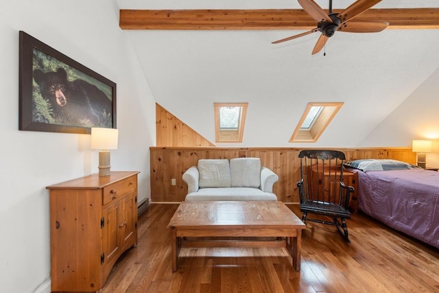 bedroom featuring hardwood / wood-style flooring, lofted ceiling with skylight, ceiling fan, and wood walls