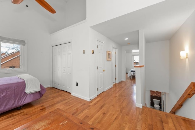 bedroom with a closet, light hardwood / wood-style floors, and ceiling fan