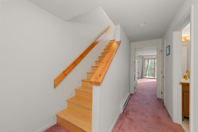 stairway with carpet flooring, a baseboard radiator, and a textured ceiling