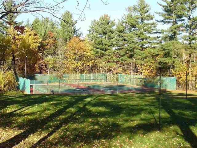 view of tennis court featuring a lawn