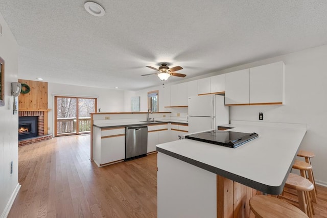 kitchen with kitchen peninsula, light wood-type flooring, stainless steel dishwasher, white cabinets, and white fridge