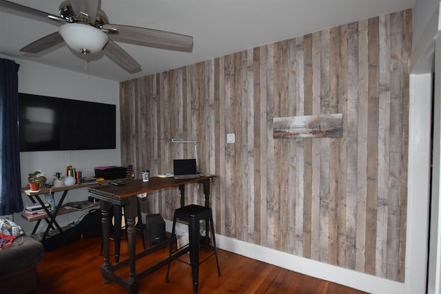 office featuring dark hardwood / wood-style floors, ceiling fan, and wood walls