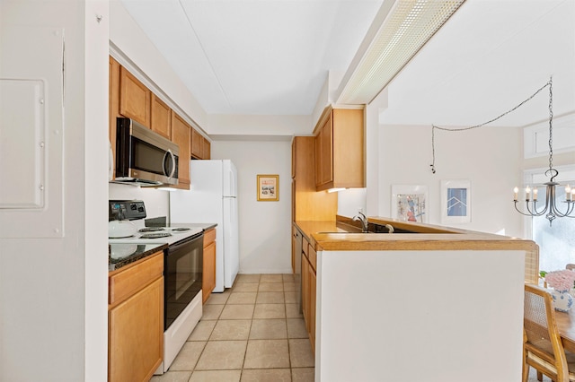 kitchen with white appliances, a kitchen breakfast bar, light tile patterned floors, kitchen peninsula, and a chandelier