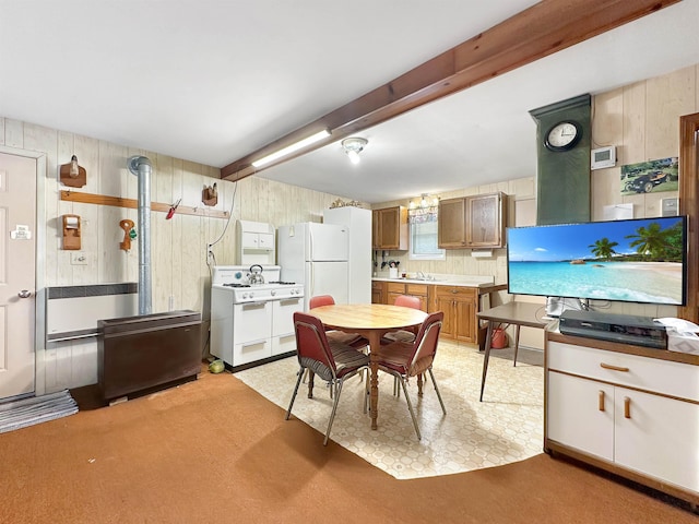 kitchen featuring wooden walls, sink, beamed ceiling, and white appliances