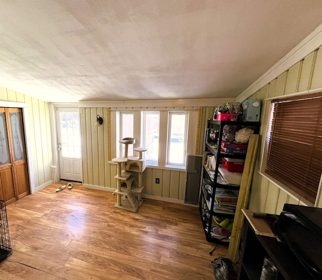 misc room with wood walls, light hardwood / wood-style flooring, and a textured ceiling