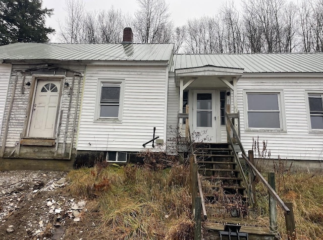 view of front of home featuring metal roof, a chimney, and entry steps