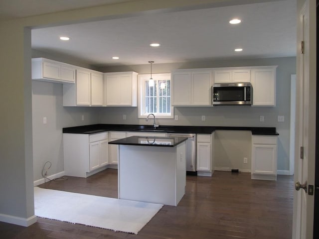 kitchen featuring appliances with stainless steel finishes, dark hardwood / wood-style flooring, decorative light fixtures, white cabinets, and a center island