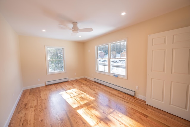 unfurnished room with ceiling fan, baseboard heating, and light hardwood / wood-style flooring