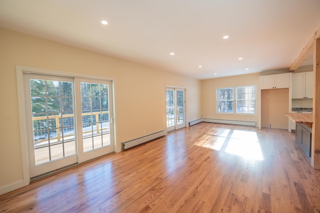 unfurnished living room featuring light hardwood / wood-style floors and a baseboard heating unit