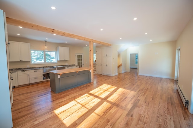 kitchen with white cabinetry, a center island, light hardwood / wood-style floors, and a baseboard heating unit