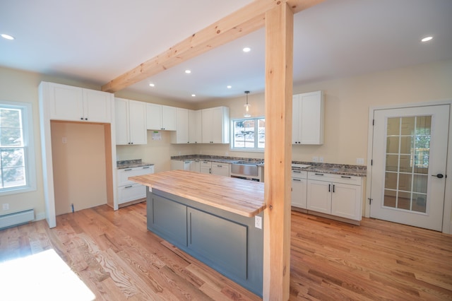 kitchen with white cabinets, plenty of natural light, and butcher block counters