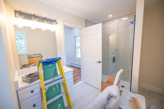 bathroom featuring baseboard heating, hardwood / wood-style floors, vanity, and plenty of natural light