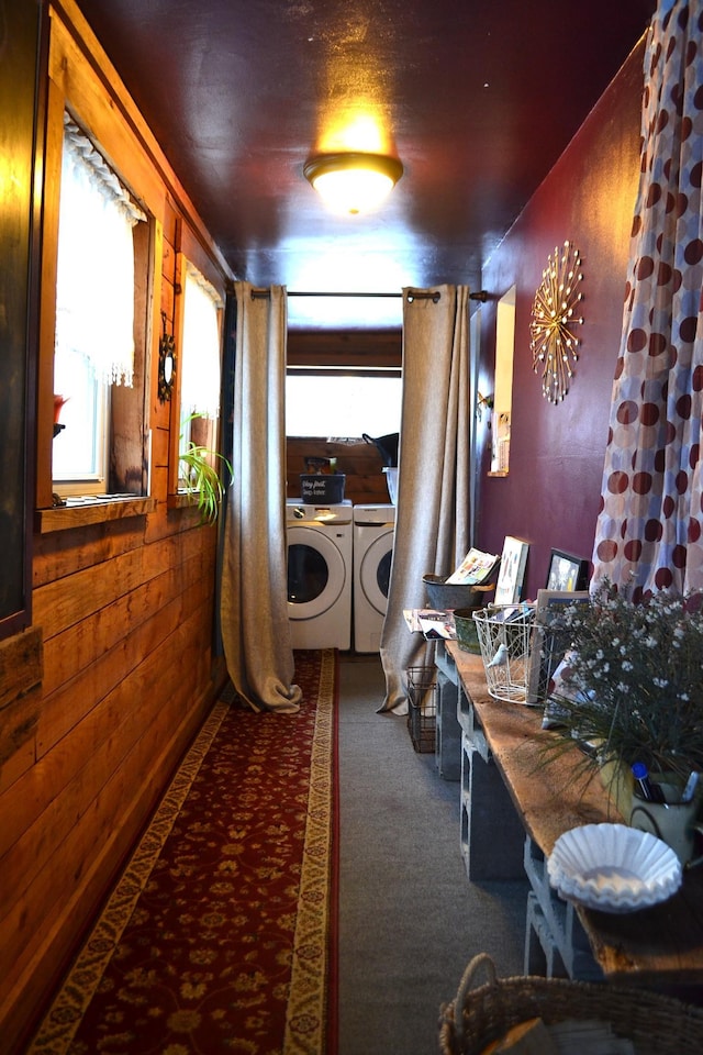 corridor featuring carpet flooring, wooden walls, and washing machine and clothes dryer