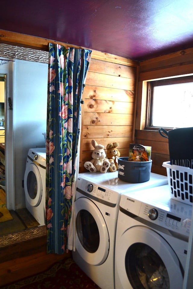 laundry room with wooden walls, washer and clothes dryer, and wood-type flooring