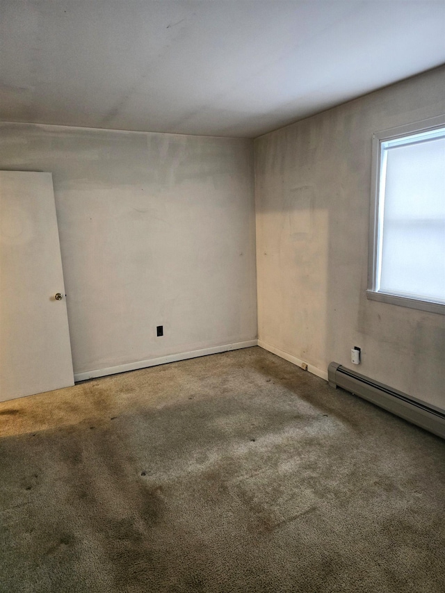 empty room with carpet floors and a baseboard heating unit