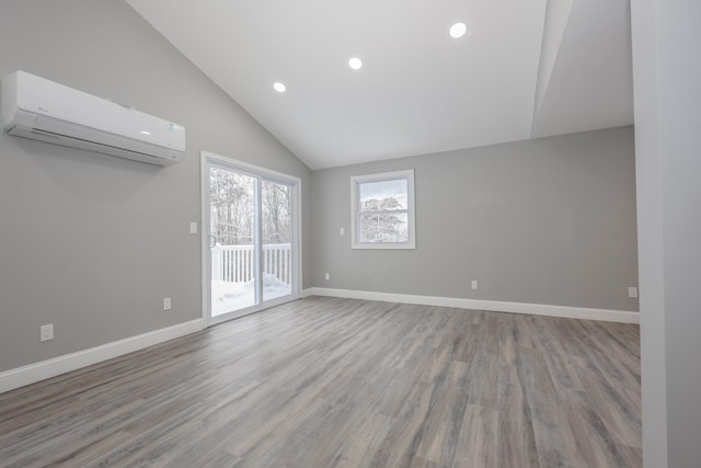 unfurnished room featuring a wall mounted air conditioner, high vaulted ceiling, and light hardwood / wood-style flooring