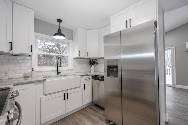 kitchen featuring appliances with stainless steel finishes, backsplash, light wood-type flooring, sink, and white cabinets