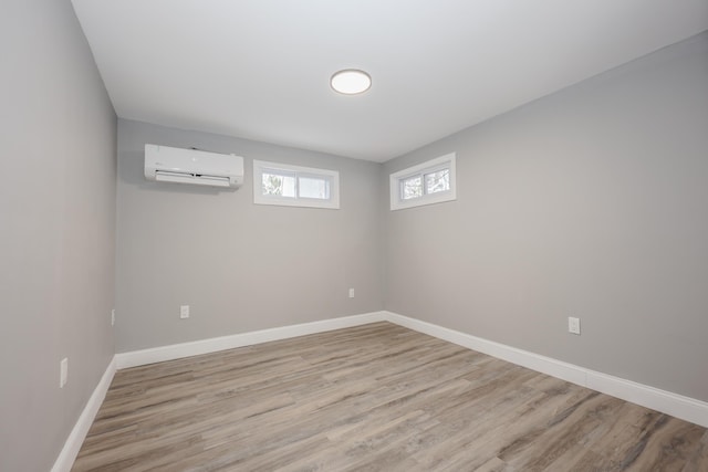 basement featuring a wall mounted air conditioner and light wood-type flooring