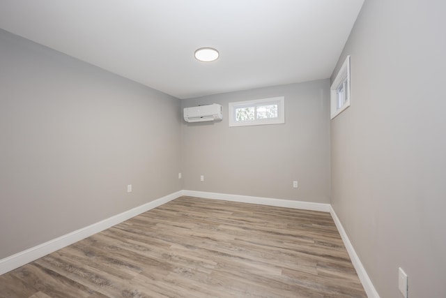 empty room featuring an AC wall unit and light wood-type flooring