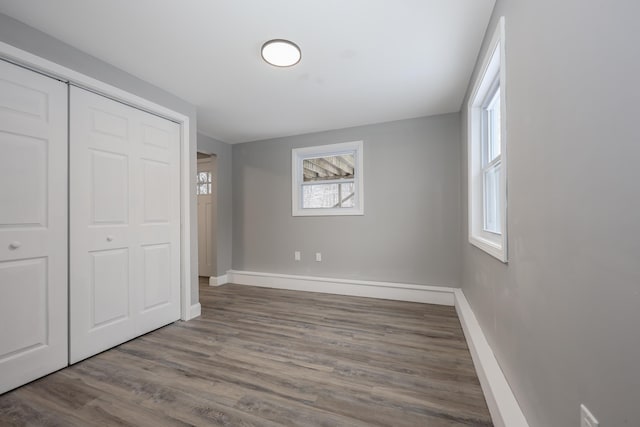 unfurnished bedroom with multiple windows, a closet, and hardwood / wood-style flooring