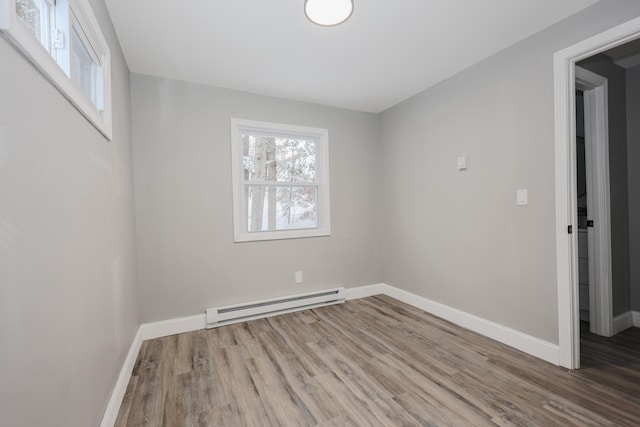 unfurnished room with hardwood / wood-style flooring and a baseboard heating unit