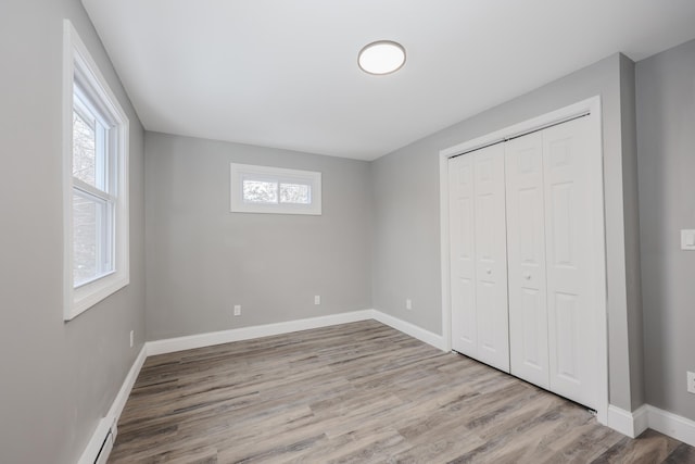 unfurnished bedroom featuring a closet, light hardwood / wood-style flooring, and multiple windows