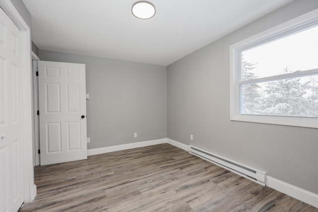 empty room with hardwood / wood-style floors and baseboard heating