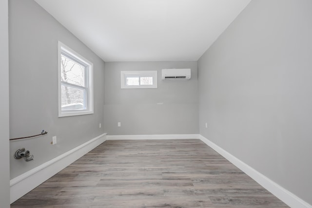 empty room with light hardwood / wood-style flooring and an AC wall unit