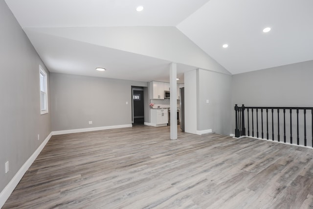 unfurnished living room with lofted ceiling and light wood-type flooring