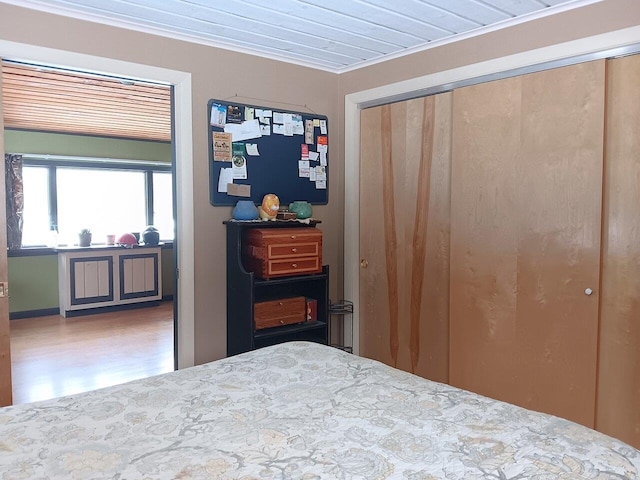 bedroom with crown molding, a closet, and hardwood / wood-style flooring