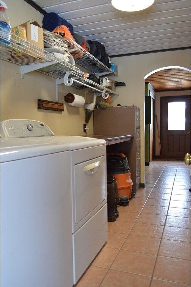 clothes washing area with washer and clothes dryer, light tile patterned flooring, and wooden ceiling