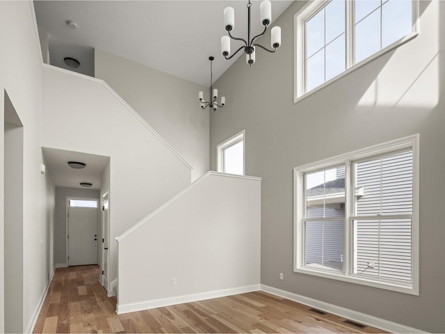 interior space with a high ceiling, light hardwood / wood-style floors, and a notable chandelier