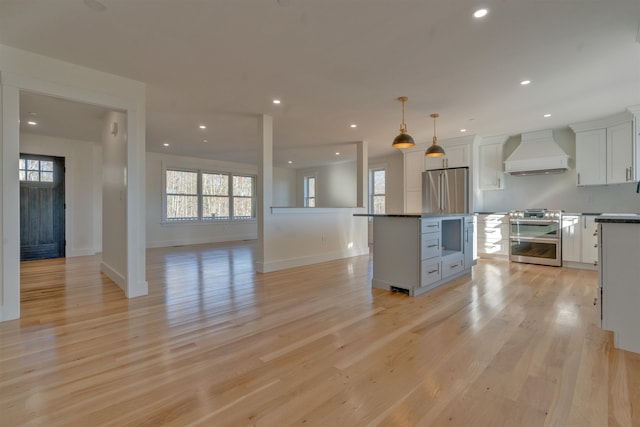 17 Durant Rd, Berwick, ME 03901 - kitchen with custom exhaust hood, appliances with stainless steel finishes, white cabinetry, a kitchen island, and light wood finished floors