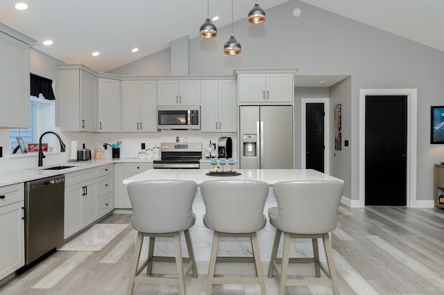 kitchen featuring appliances with stainless steel finishes, decorative light fixtures, a kitchen island, and sink