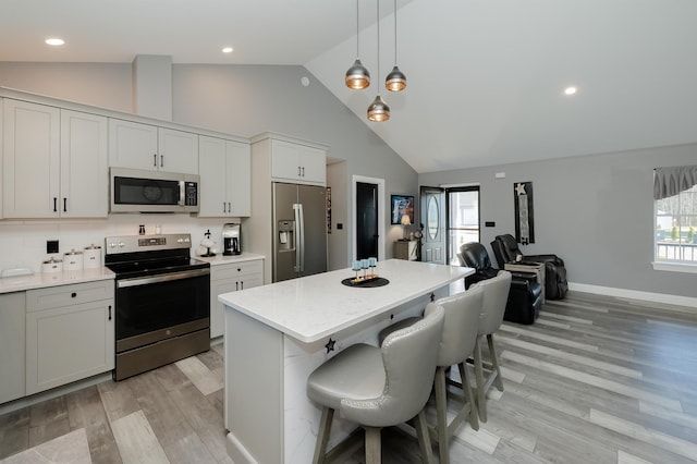 kitchen with a kitchen bar, plenty of natural light, stainless steel appliances, and light wood-type flooring