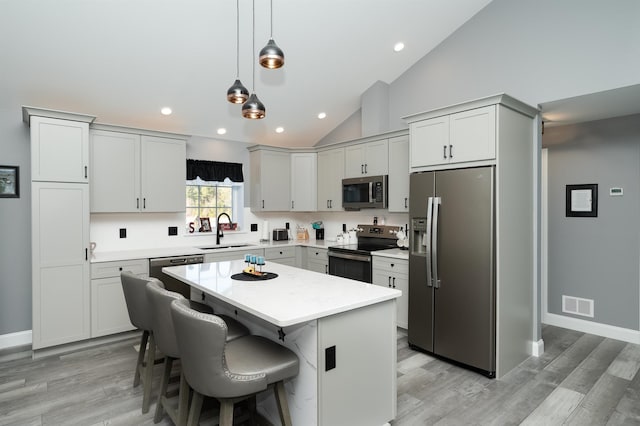 19 Whippoorwill Way, Somersworth, NH 03878 - kitchen featuring appliances with stainless steel finishes, a kitchen island, light countertops, decorative light fixtures, and light wood-style floors